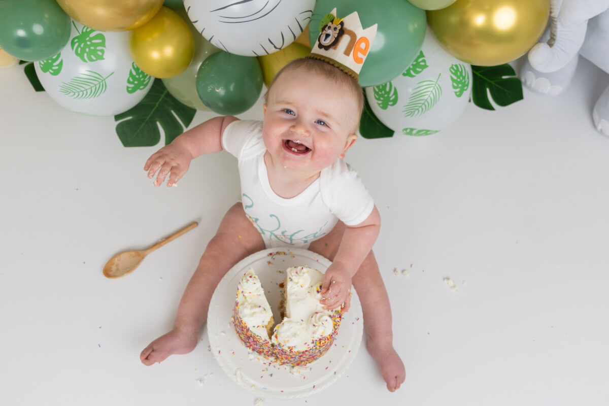 Overhead view of laughing baby boy with cake on first birthday
