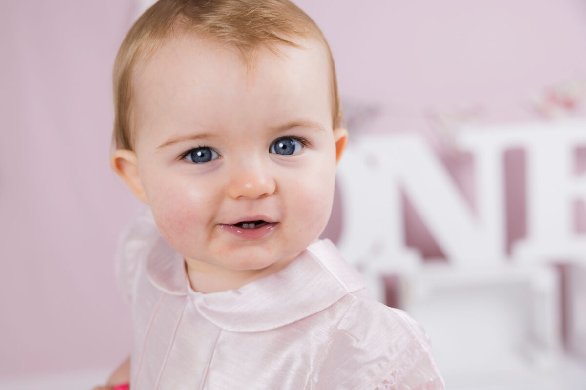 Close-up of a baby girl with blue eyes and pink dress