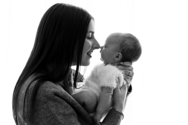 Black and white portrait of mother gazing at newborn baby.