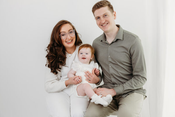 Natural mother, father and daughter portrait captured before a first birthday cake smash.