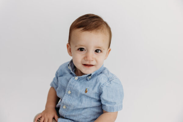 Baby boy against white background during first birthday photoshoot