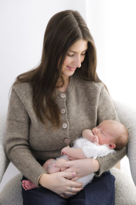 Mother holding newborn baby while seated.