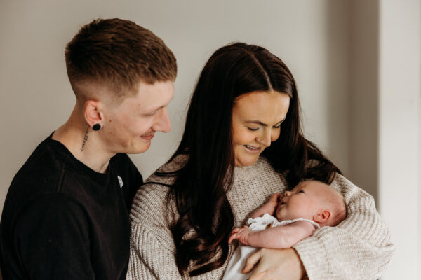 Parents cuddling their children during a relaxed family photoshoot.