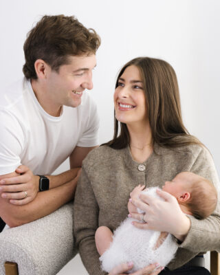 Parents smiling with their newborn baby.