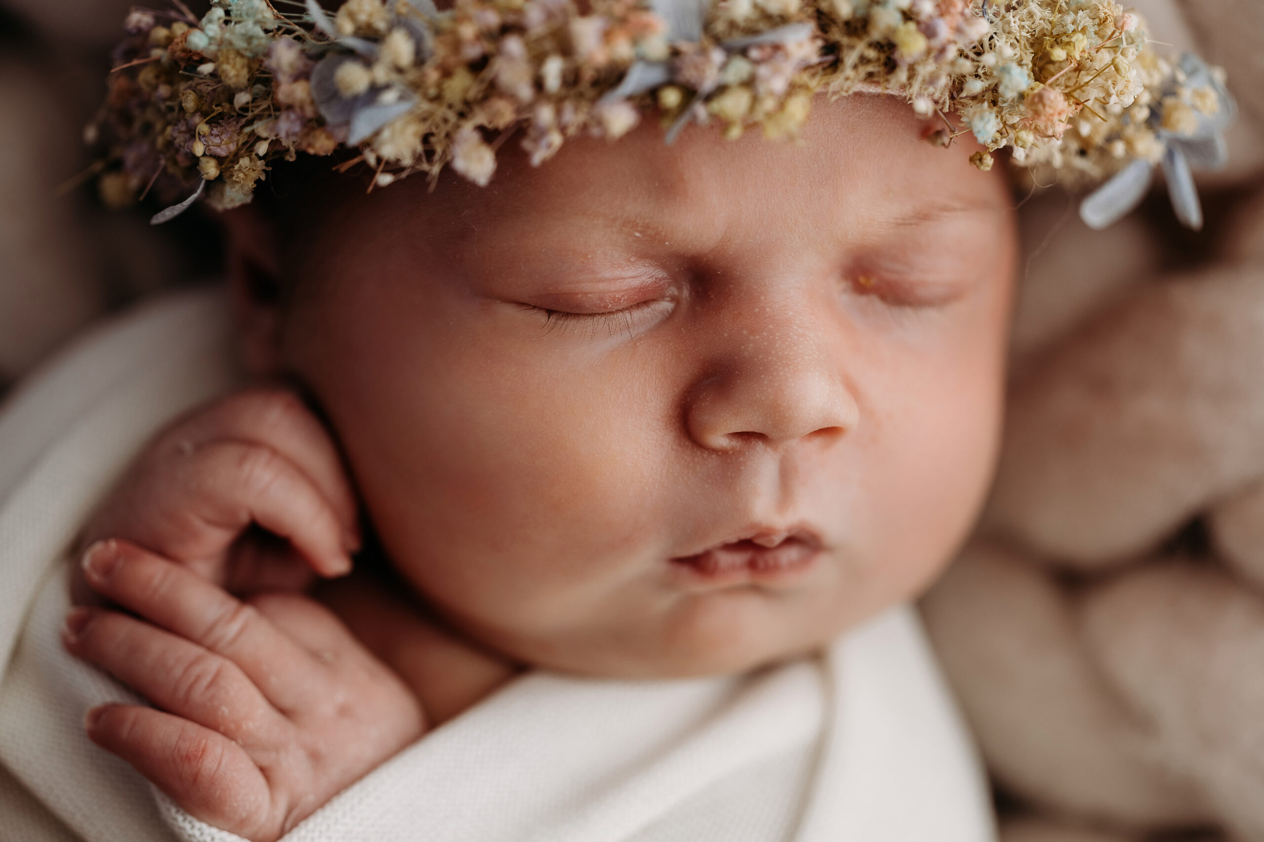 Sleeping newborn wearing dried-flower crown.